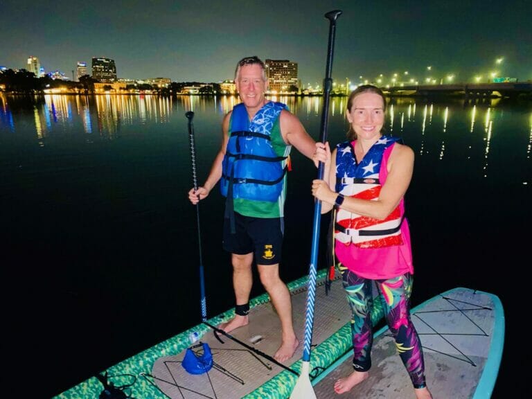 Happy Couple riding paddleboards in orlando at night